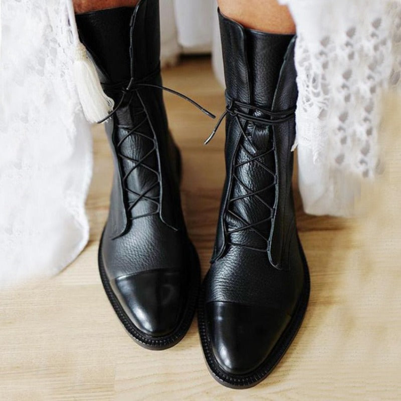 Schwarze Damenstiefel aus Leder mit Schnürung, getragen auf hellem Holzboden. Modische, elegante Stiefel für Herbst und Winter.