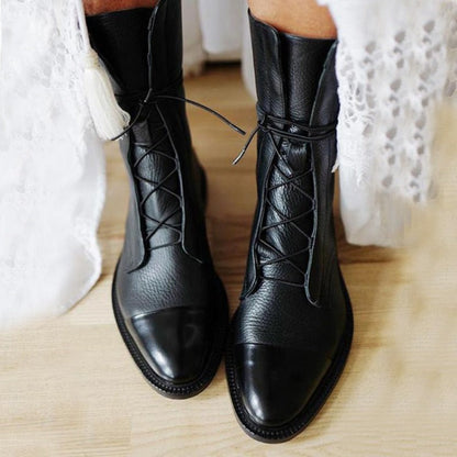 Schwarze Damenstiefel aus Leder mit Schnürung, getragen auf hellem Holzboden. Modische, elegante Stiefel für Herbst und Winter.
