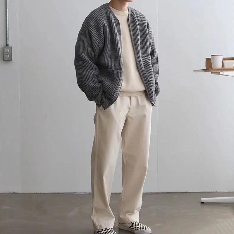 Grauer Strick-Cardigan, cremefarbenes Shirt und Hose, lässiger Herren-Look, minimalistisch, moderne Mode, gemütlicher Stil, Indoor-Aufnahme.