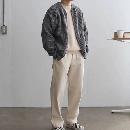 Grauer Strick-Cardigan, cremefarbenes Shirt und Hose, lässiger Herren-Look, minimalistisch, moderne Mode, gemütlicher Stil, Indoor-Aufnahme.