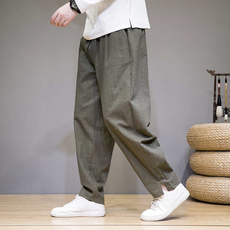 Graue Herren-Haremshose mit Nadelstreifen, kombiniert mit weißen Sneakers. Bequeme, lässige Mode für Männer. Ideal für Freizeit und Alltag.