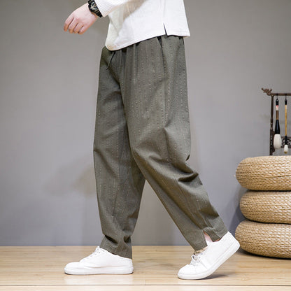 Graue Herren-Haremshose mit Nadelstreifen, kombiniert mit weißen Sneakers. Bequeme, lässige Mode für Männer. Ideal für Freizeit und Alltag.