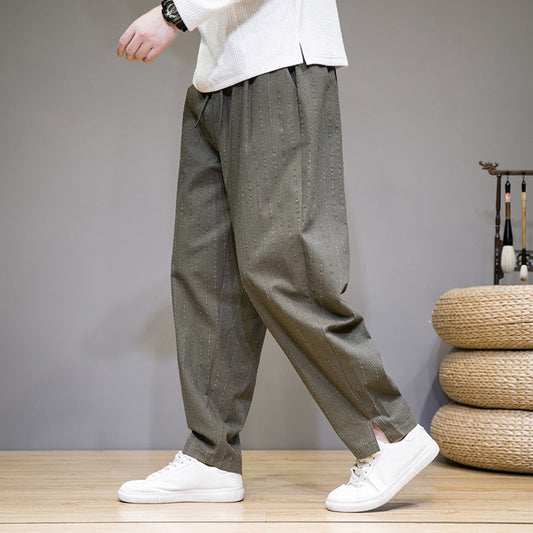 Graue Herren-Haremshose mit Nadelstreifen, kombiniert mit weißen Sneakers. Bequeme, lässige Mode für Männer. Ideal für Freizeit und Alltag.