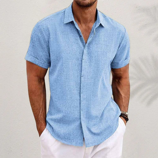 Mann in hellblauem Leinenhemd und weißen Shorts vor neutralem Hintergrund. Sommermode, Herrenbekleidung, lässiger Stil.