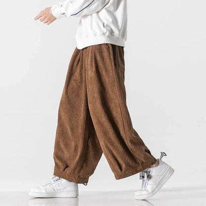 Person in weißen Sneakers und brauner Cordhose, die seitlich geht. Modetrend, lässiger Stil, Herrenbekleidung, bequeme Passform.