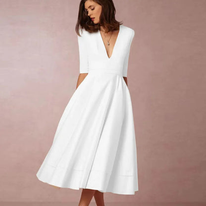 Frau in elegantem weißen Kleid mit V-Ausschnitt und halblangen Ärmeln vor rosa Hintergrund. Mode, Damenbekleidung, Abendkleid.