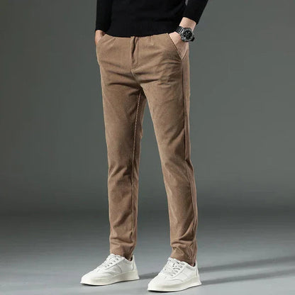 Braune Cordhose für Herren, kombiniert mit weißem Sneaker und schwarzem Pullover. Modischer, lässiger Look, ideal für Herbst und Winter.