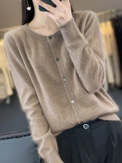 Frau in braunem Strickcardigan mit Knöpfen, hält Smartphone. Modetrend Herbst, elegante Damenbekleidung, gemütlicher Look.