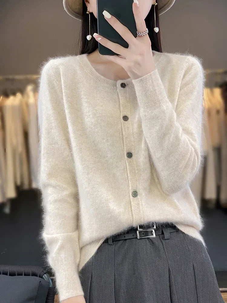Frau in cremefarbenem Strickcardigan mit Knöpfen, graue Hose, modisches Outfit, Herbstmode, eleganter Look, Kleidungsgeschäft im Hintergrund.