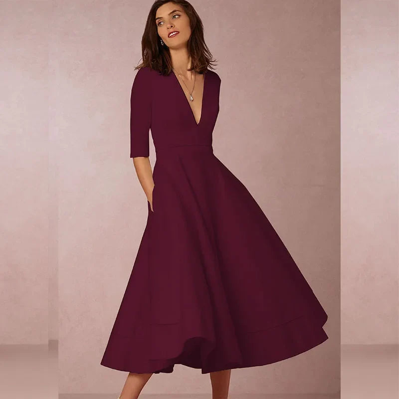 Frau in elegantem, weinrotem Abendkleid mit V-Ausschnitt und halblangen Ärmeln vor neutralem Hintergrund. Perfekt für festliche Anlässe.