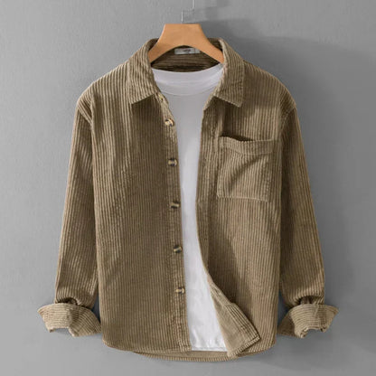 Braunes Cordhemd auf Kleiderbügel, über weißem T-Shirt. Modische Herrenbekleidung, lässiger Stil, ideal für Herbstmode und Freizeitoutfits.