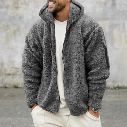 Mann trägt graue Fleecejacke mit Kapuze, lässiger Stil, Herbstmode, Outdoor-Bekleidung, warm und bequem, ideal für kühle Temperaturen.