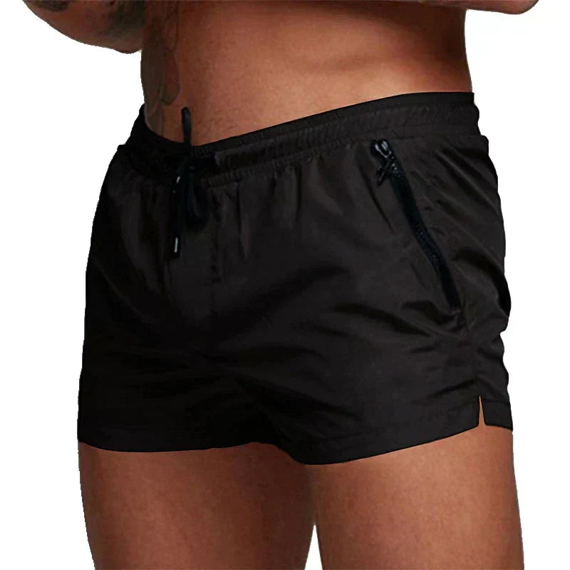 Schwarze Herren-Badeshorts mit Kordelzug und Reißverschlusstaschen, ideal für Strand und Schwimmen. Sportliche, bequeme Passform.