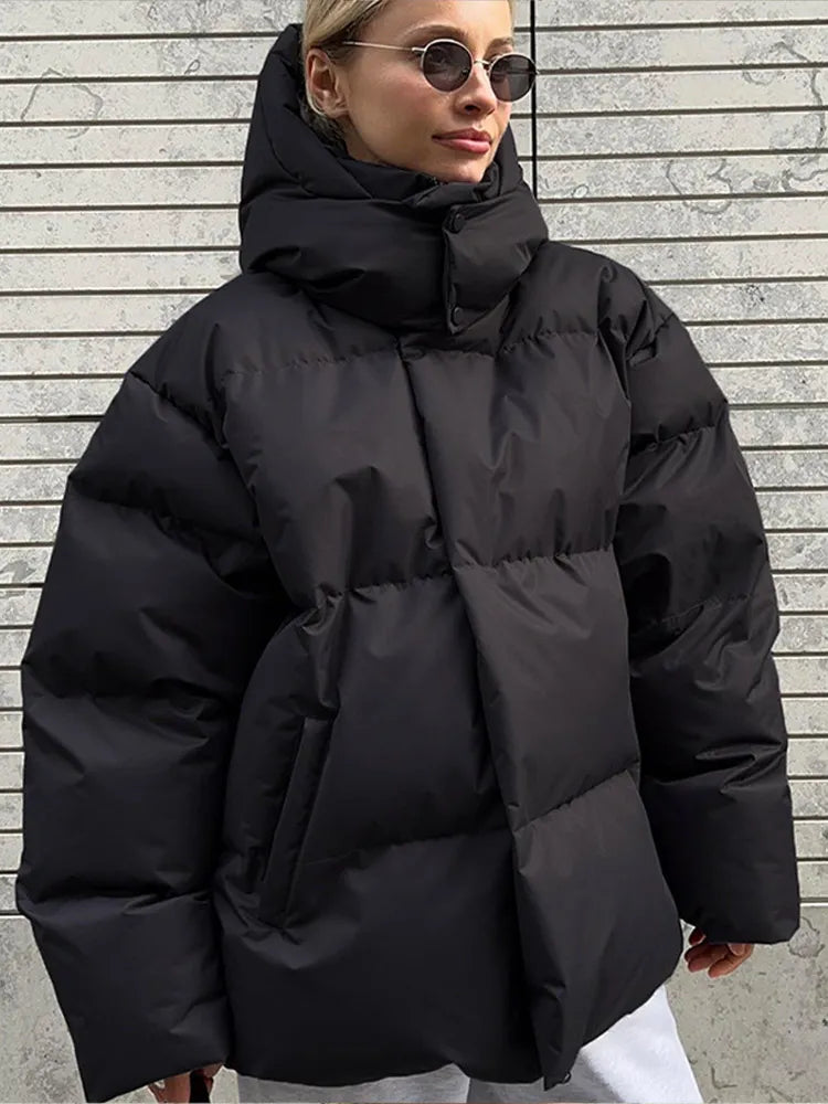 Frau in schwarzer Daunenjacke vor gestreifter Wand, trägt Sonnenbrille. Wintermode, stylische Damenbekleidung, warme Jacke, modischer Look.