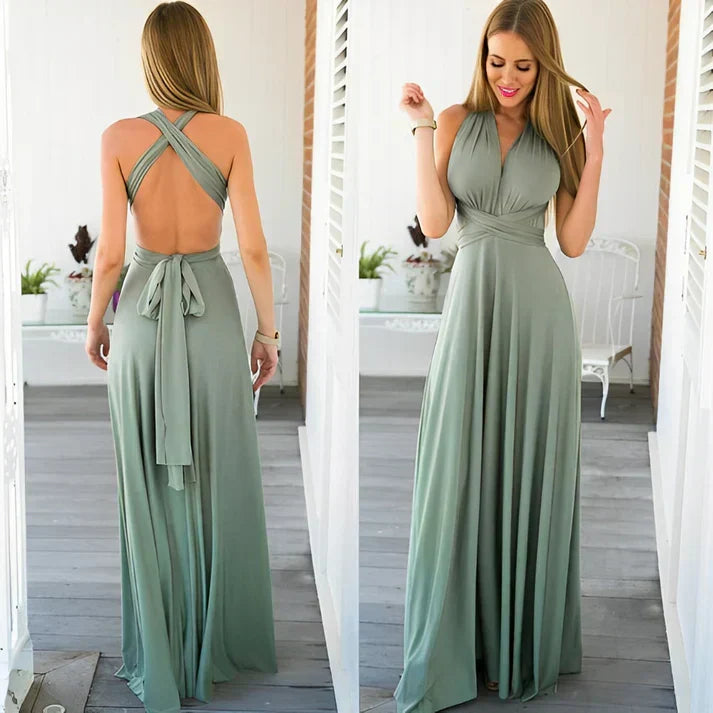 Frau in langem, grünem Abendkleid mit Rückenausschnitt und Wickeldesign, steht auf Veranda. Elegantes, modernes Modeoutfit für besondere Anlässe.
