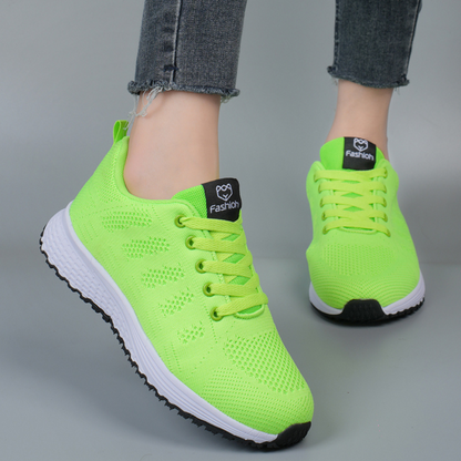 Neon-grüne Sportschuhe mit weißer Sohle, getragen von Person in Jeans. Modische, atmungsaktive Sneaker für Damen, ideal für Laufen und Freizeit.