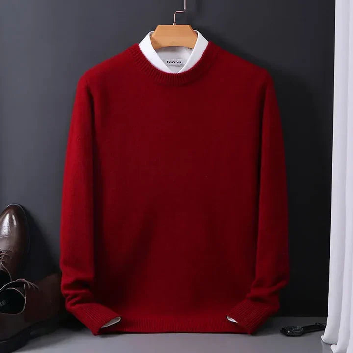 Roter Pullover aus Wolle auf Kleiderbügel, kombiniert mit weißem Hemdkragen, neben braunen Lederschuhen. Elegante Herrenmode, Herbst-Winter-Stil.