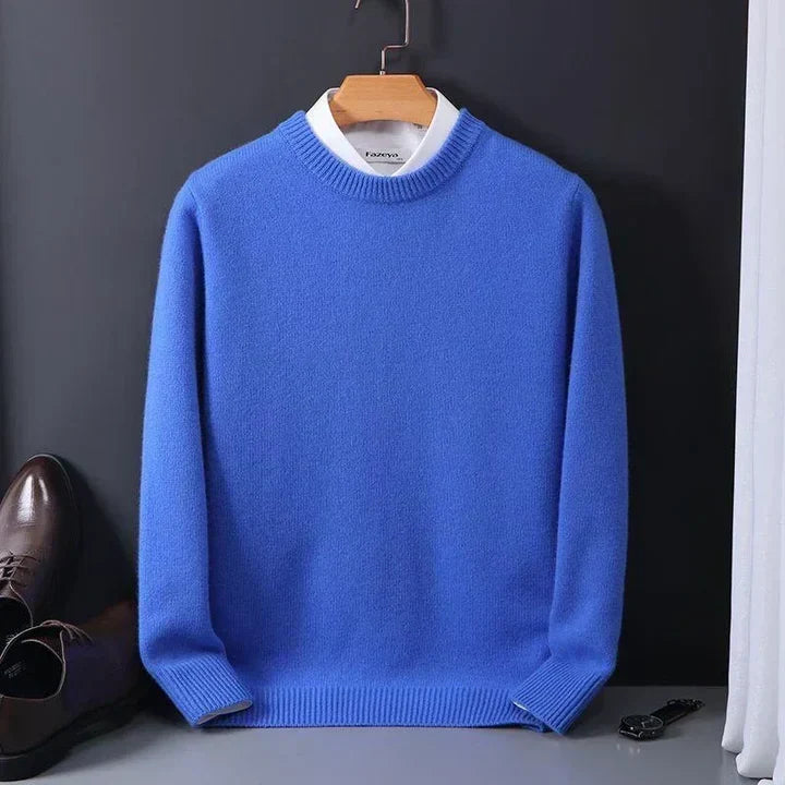 Blauer Herrenpullover aus Wolle auf Kleiderbügel, kombiniert mit weißem Hemd. Elegante Mode, ideal für Herbst und Winter.