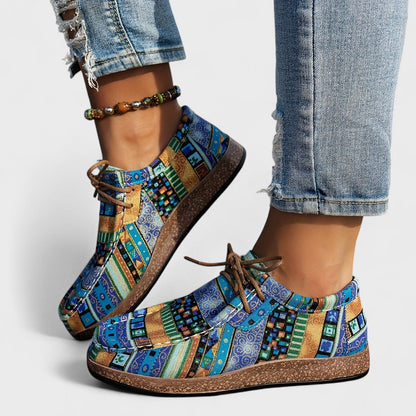 Bunte Patchwork-Sneaker mit blau-grünem Muster, getragen mit zerrissenen Jeans und Perlenfußkettchen. Modische Freizeitschuhe für Damen.