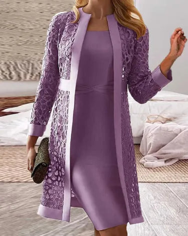 Frau in lila Spitzenkleid mit passendem Mantel, hält eine schwarze Clutch. Elegantes Outfit für besondere Anlässe.