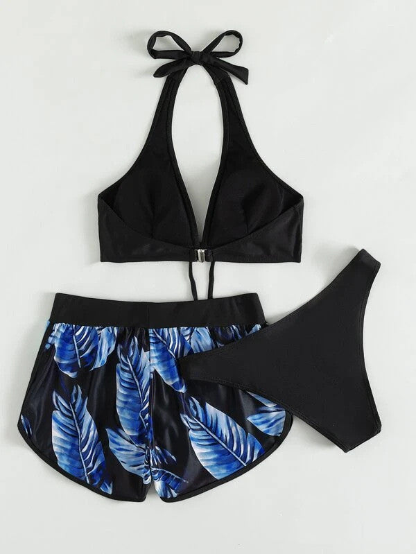 Damen-Bikini-Set mit schwarzem Neckholder-Oberteil, blauen Blattmuster-Shorts und schwarzem Slip. Sommermode, Strandbekleidung, Bademode.