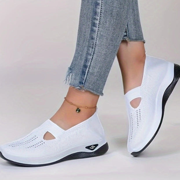 Weiße Damen-Sneaker mit Keilabsatz, atmungsaktivem Mesh-Obermaterial und schwarzer Sohle, getragen mit blauen Jeans. Ideal für Freizeit und Komfort.
