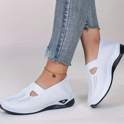 Weiße Damen-Sneaker mit Keilabsatz, atmungsaktivem Mesh-Obermaterial und schwarzer Sohle, getragen mit blauen Jeans. Ideal für Freizeit und Komfort.