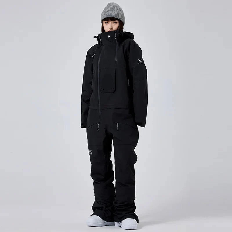 Person in schwarzer Winterjacke und Hose, graue Mütze, weiße Schuhe, vor grauem Hintergrund. Wintermode, Outdoor-Bekleidung, Skibekleidung.