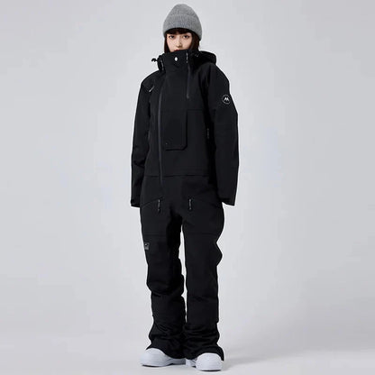 Person in schwarzer Winterjacke und Hose, graue Mütze, weiße Schuhe, vor grauem Hintergrund. Wintermode, Outdoor-Bekleidung, Skibekleidung.