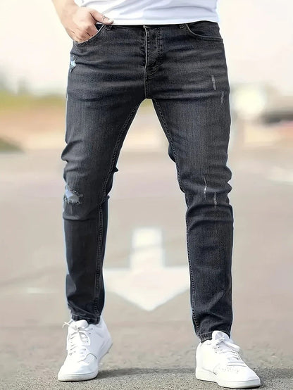 Mann in dunkler Jeans und weißen Sneakers auf Straße. Modetrend, Herrenbekleidung, lässiger Stil, Denim, Freizeitlook.