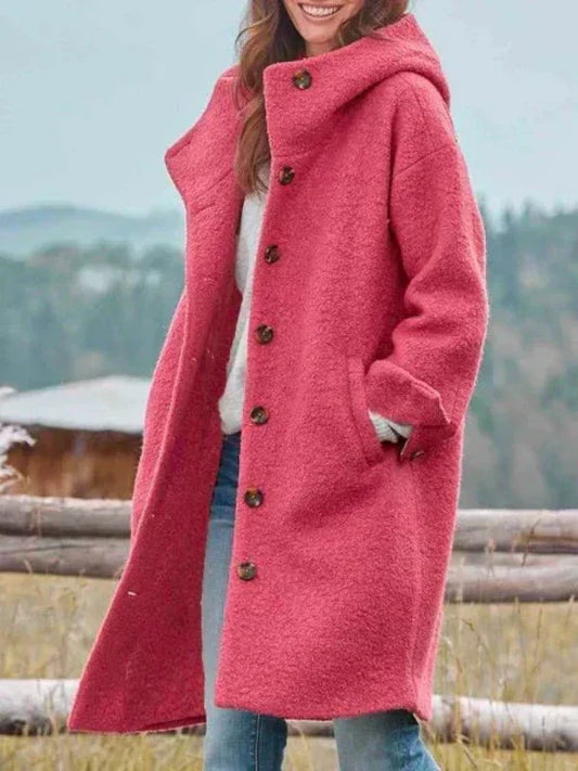 Frau in rosa Wollmantel mit Kapuze und Knöpfen, lächelnd im Freien. Modischer Wintermantel, ideal für kalte Tage.