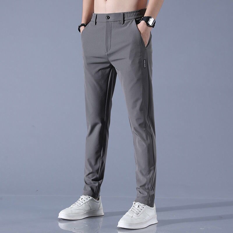 Graue Herren-Chinohose, modern geschnitten, kombiniert mit weißen Sneakers. Ideal für Freizeit und Büro. Eleganter, zeitloser Stil.