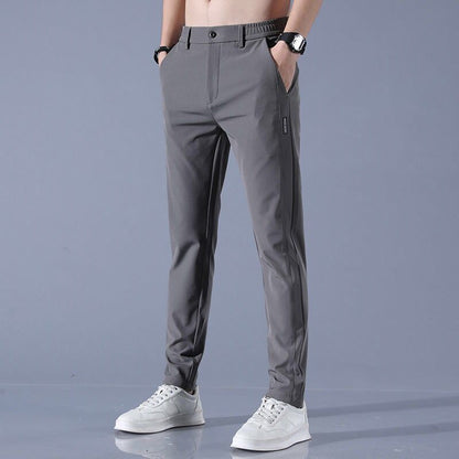 Graue Herren-Chinohose, modern geschnitten, kombiniert mit weißen Sneakers. Ideal für Freizeit und Büro. Eleganter, zeitloser Stil.