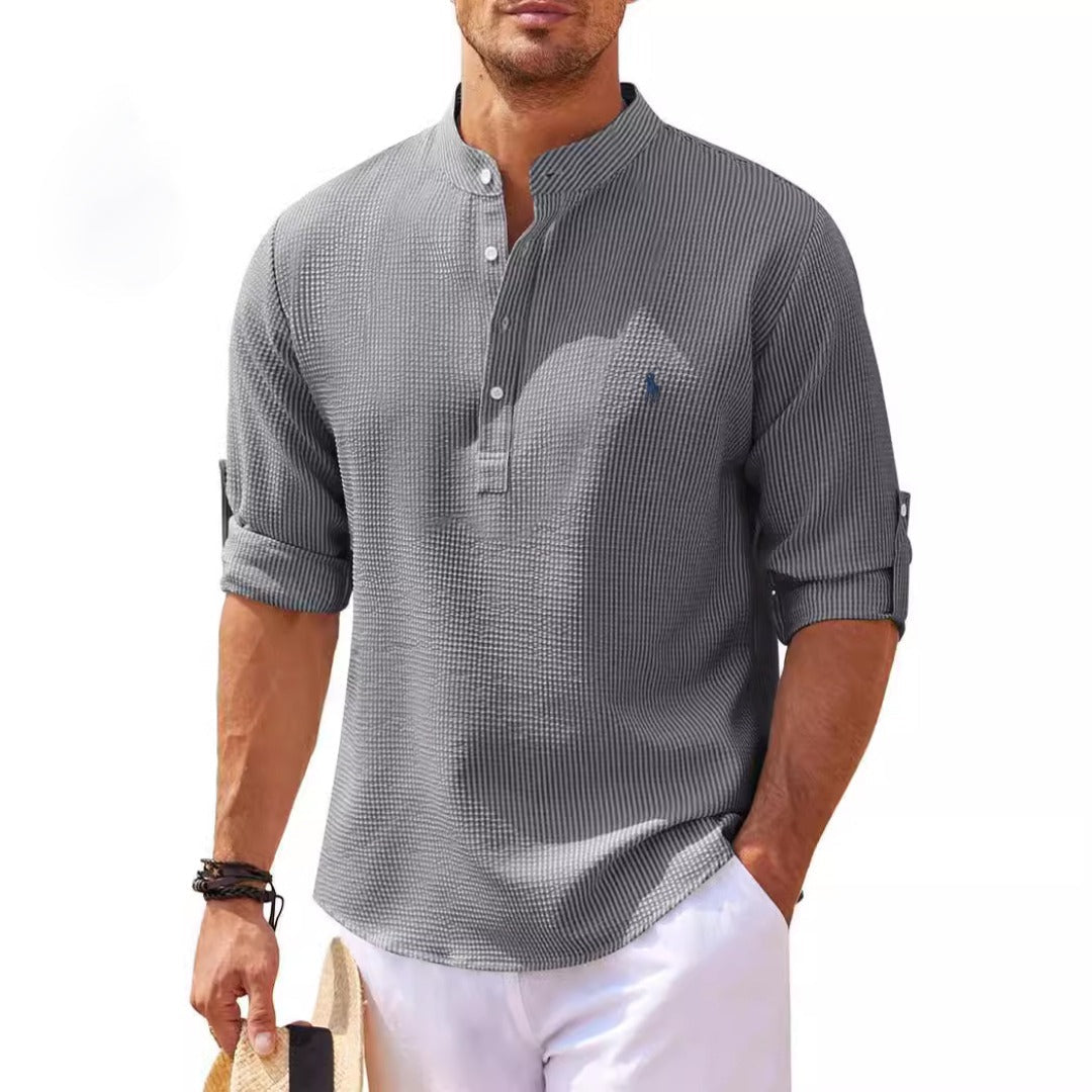 Graues Herrenhemd mit Stehkragen und hochgekrempelten Ärmeln, getragen von einem Mann. Sommermode, Freizeitlook, stilvoll und modern.
