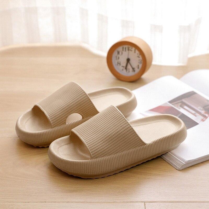 Beige Hausschuhe auf Holztisch, neben einer Uhr und einem Magazin. Komfortable, rutschfeste Pantoffeln für Zuhause. Ideal für gemütliche Abende.