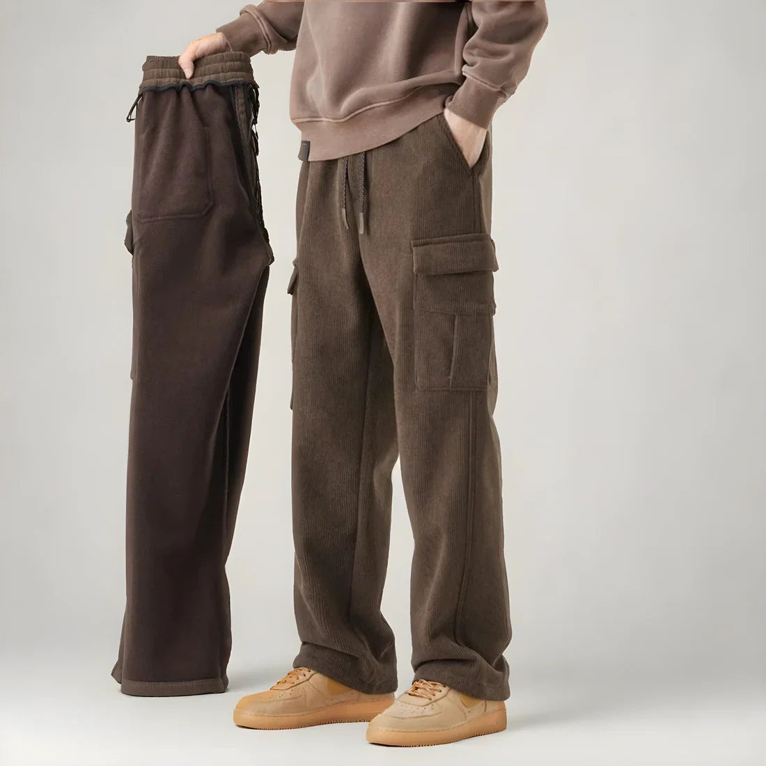 Zwei braune Cargohosen aus Fleece, eine getragen, eine gehalten, mit Seitentaschen. Perfekt für Herrenmode, Freizeitkleidung, Herbsttrends.