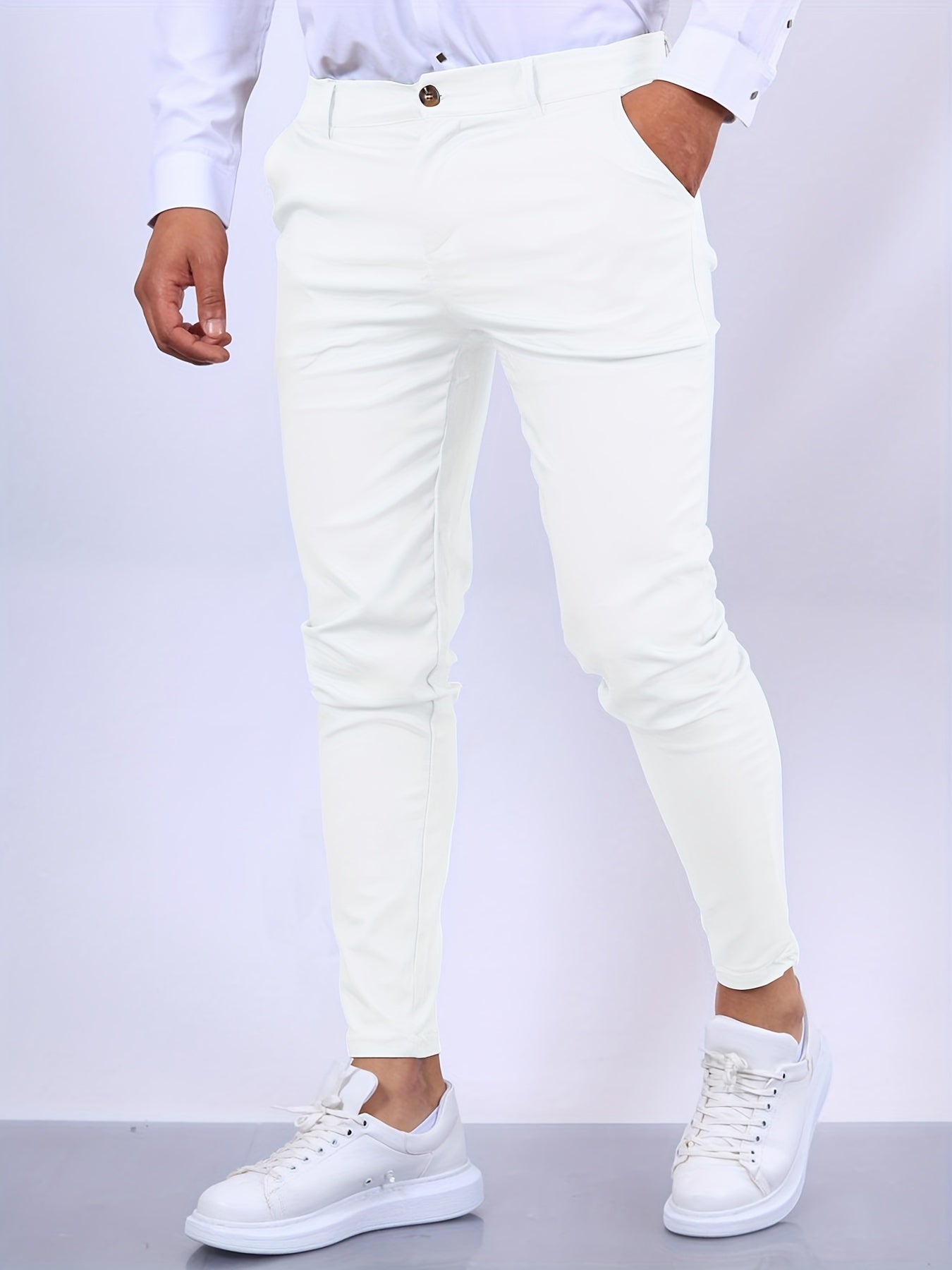 Mann in weißen Slim-Fit-Hosen und weißen Sneakers, modisch und elegant. Perfekt für stilvolle Herrenmode und Freizeitoutfits.