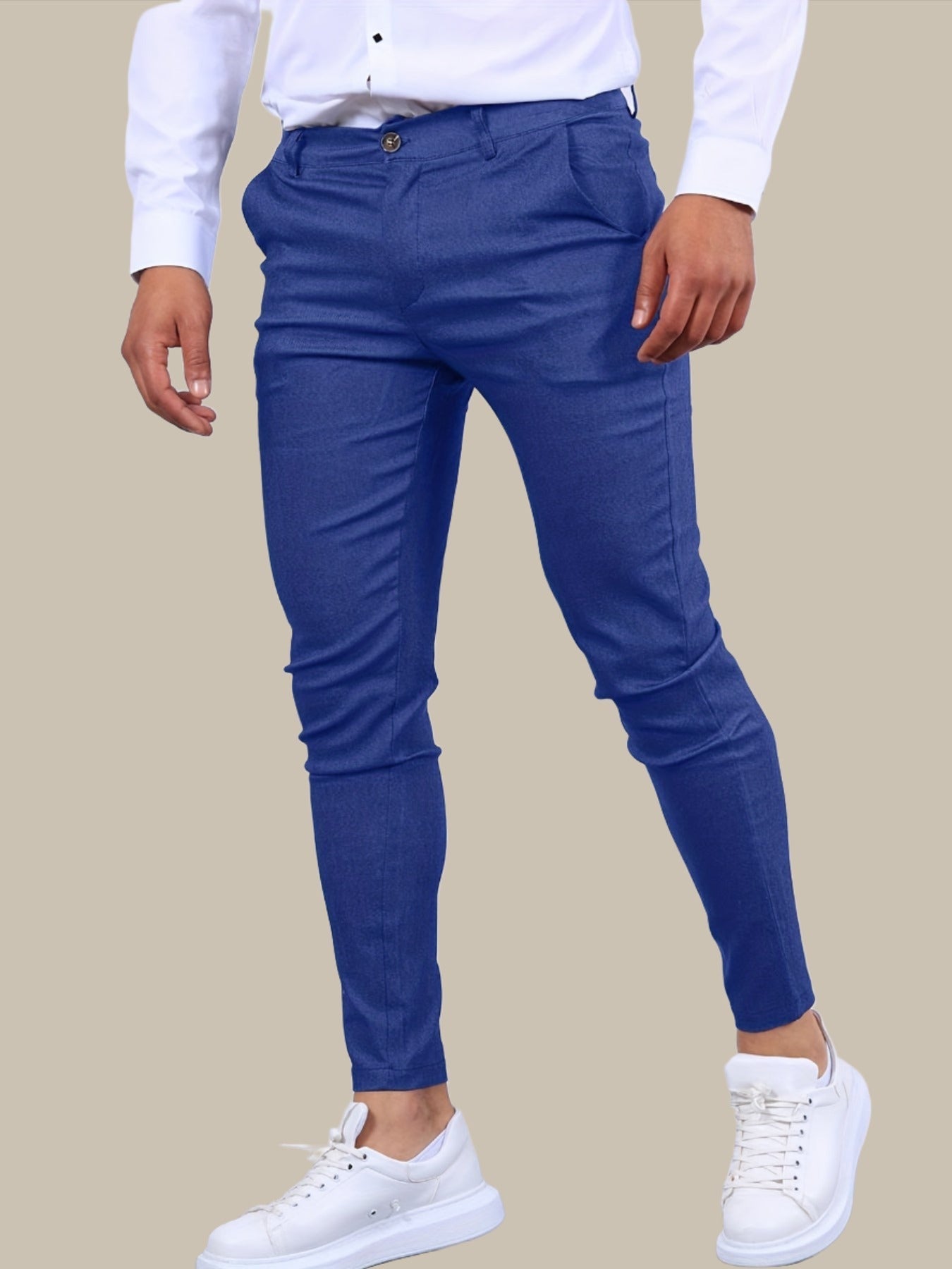 Mann in blauer Slim-Fit-Hose und weißen Sneakers, trägt weißes Hemd. Modische Herrenbekleidung, eleganter Look, moderne Herrenmode.
