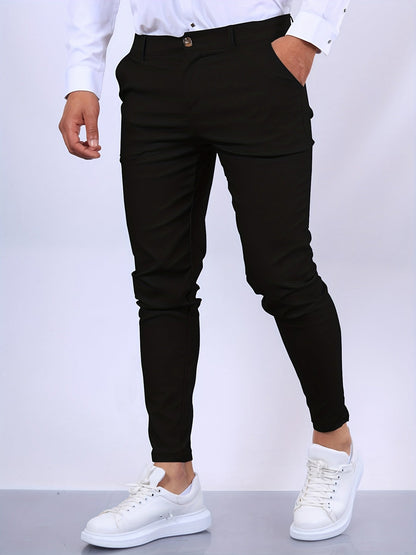 Mann in schwarzer Hose und weißen Sneakers vor weißem Hintergrund. Modische Herrenbekleidung, elegante Hose, lässige Schuhe.