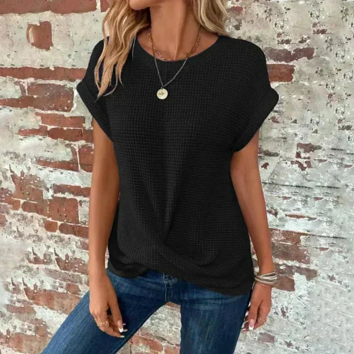 Frau in schwarzem T-Shirt und blauer Jeans vor Backsteinmauer, lässiger Look, modisches Outfit, Sommermode, Damenbekleidung, Streetstyle.
