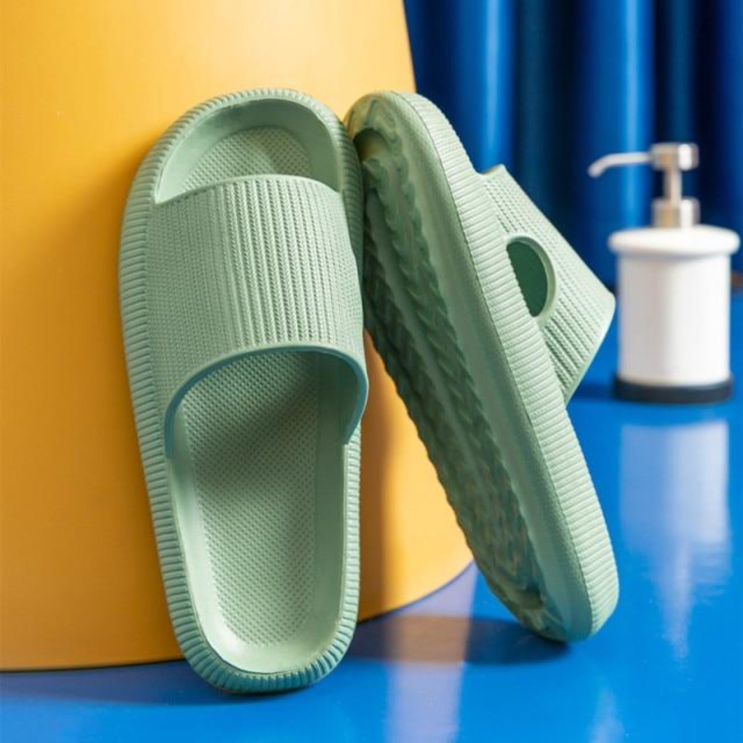 Grüne Badeschlappen aus Gummi vor gelbem Hintergrund, ideal für Badezimmer oder Pool. Komfortable, rutschfeste Hausschuhe für Damen und Herren.