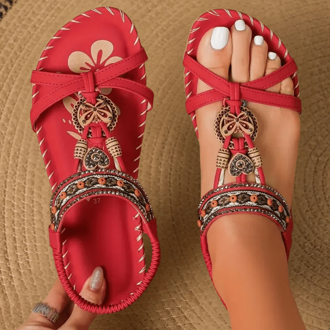 Rote Sandalen mit ethnischen Verzierungen, Perlen und Blumenmuster auf geflochtenem Teppich. Damenmode, Sommerschuhe, Boho-Stil.