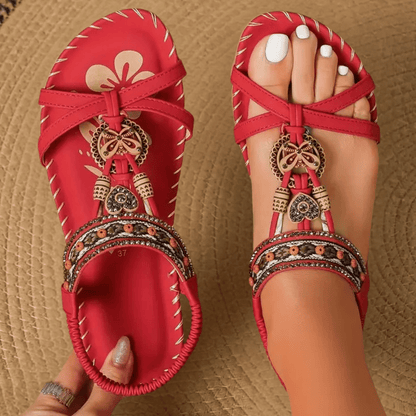 Rote Sandalen mit ethnischen Verzierungen, Perlen und Blumenmuster auf geflochtenem Teppich. Damenmode, Sommerschuhe, Boho-Stil.