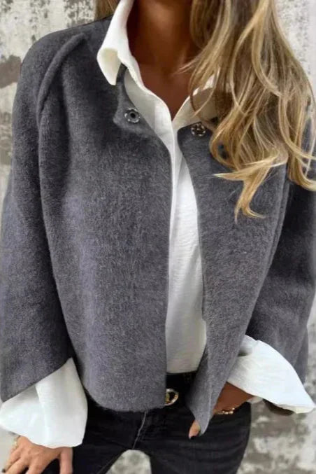 Frau in grauem Wollmantel und weißer Bluse, modisch gekleidet, lässiger Look, Herbstmode, elegante Damenbekleidung, trendiger Stil.