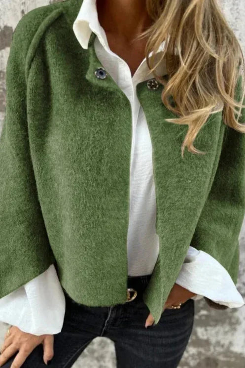 Grüne Damenjacke aus Wolle, kombiniert mit weißer Bluse und schwarzer Jeans. Modetrend Herbst, stilvolle Damenbekleidung, elegantes Outfit.