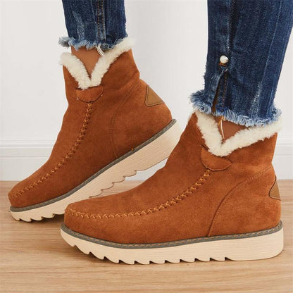 Braune Damen-Winterstiefel aus Wildleder mit weißem Kunstfellfutter, getragen zu blauen Jeans. Bequeme, modische Schuhe für kalte Tage.