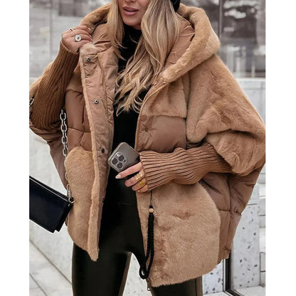 Frau in modischer, brauner Daunenjacke mit Kapuze, hält Smartphone und schwarze Handtasche. Wintermode, Streetstyle, trendige Damenbekleidung.