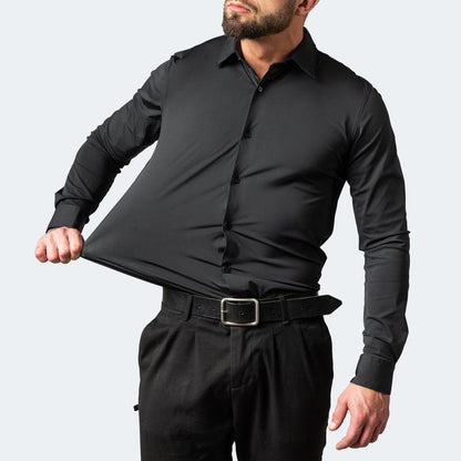 Mann in schwarzem, elastischem Hemd zieht am Stoff, um Flexibilität zu demonstrieren. Modische Herrenbekleidung, dehnbares Material, elegantes Design.