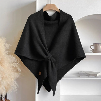 Schwarzer Wollponcho auf Kleiderbügel, minimalistisch, elegant, Herbstmode, Damenbekleidung, gemütlich, stilvoll, modernes Design, Wohnzimmerdekor.