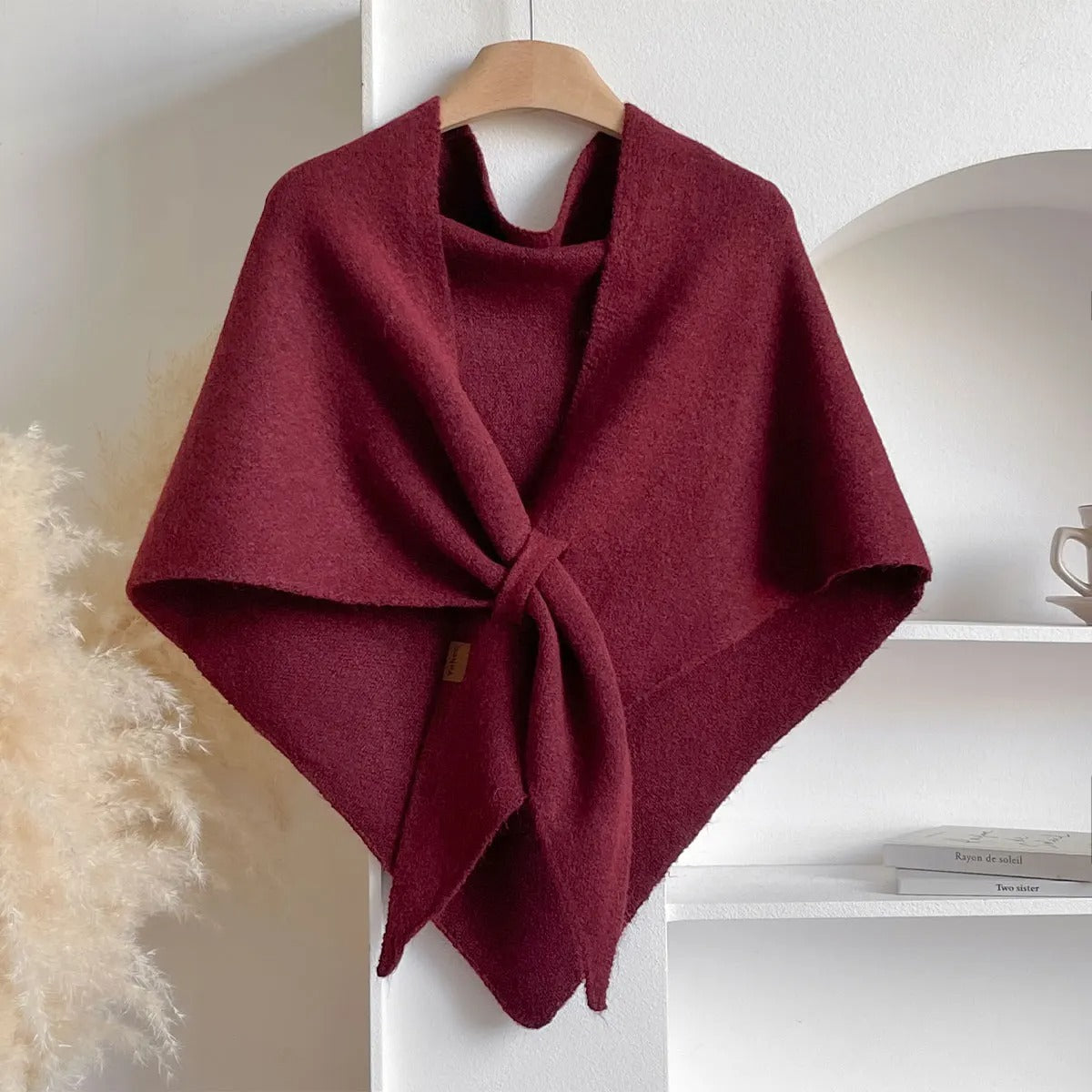 Bordeauxrotes Wolltuch auf Holzkleiderbügel, elegant drapiert. Perfekt für Herbstmode, Damenaccessoire, stilvoller Schal für kühle Tage.